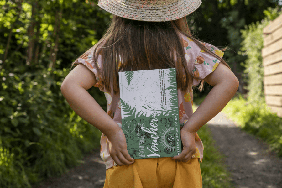 child holding foraging course voucher behind back